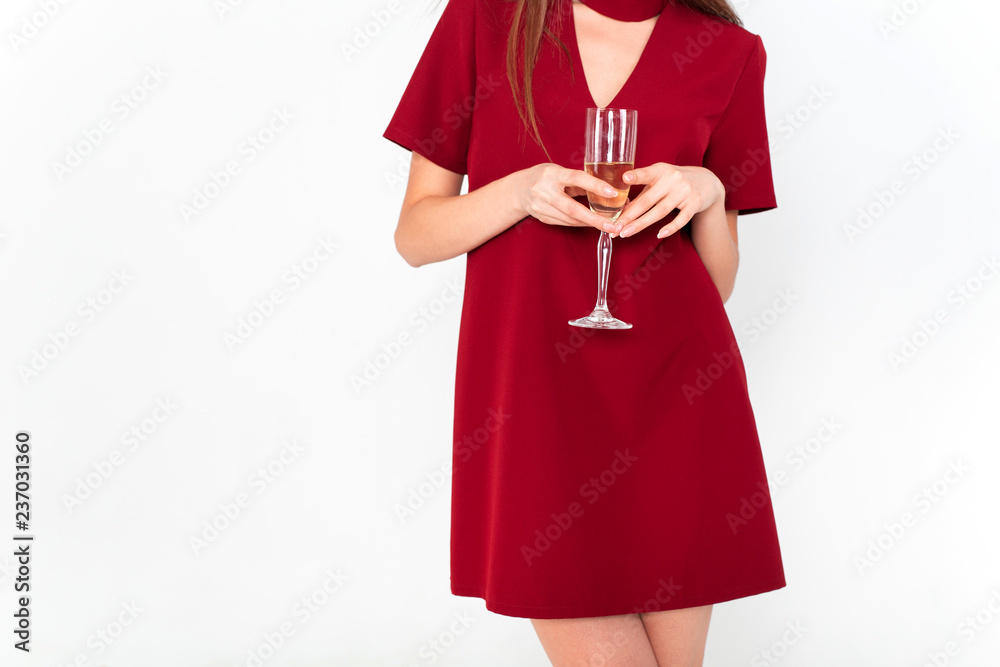 Beautiful brunette woman wearing elegant red dress holding a glass of champagne in her hand on white background