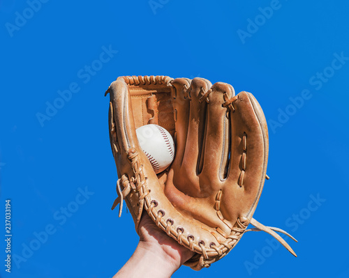 Hand in glove for a baseball game caught a leather white ball on a blue sky background. Sports contests. Victory. Achievement of success. photo