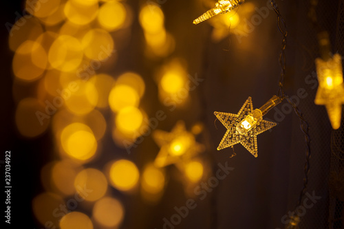 Garland in the form of stars. Blurry lights. Yellow light