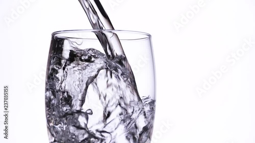 crystal clear water is poured into a glass, in slow motion, close-up