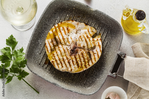 swordfish steak fried  on grill pan with olive oil and spices. white wine glass photo