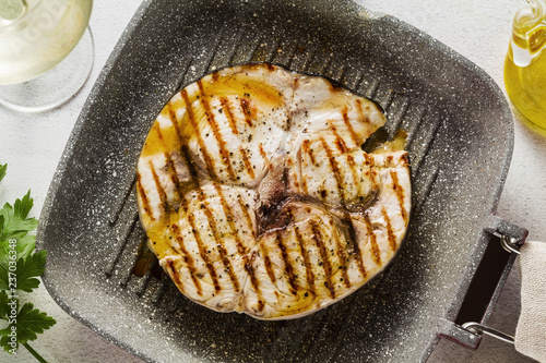 swordfish steak fried  on grill pan with olive oil and spices. white wine glass photo