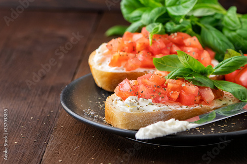 Traditional toasted Italian tomato bruschetta with spice and basil on dark wooden background