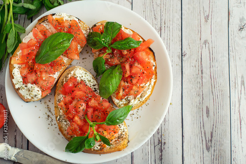 Traditional toasted Italian tomato bruschetta with spice and basil on light wooden background. Top view vith copy space photo