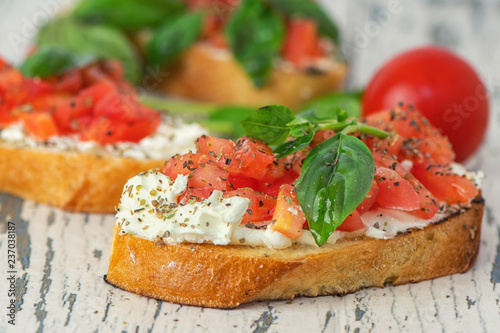 Traditional toasted Italian tomato bruschetta with spice and basil on on light wooden background. Close up