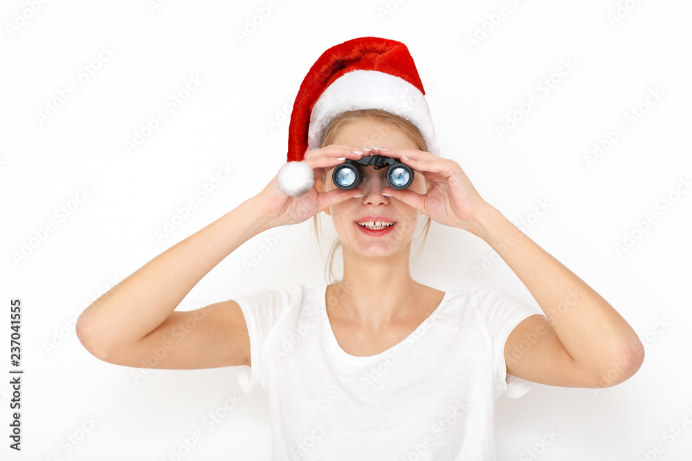 Portrait of happy  female model in new year red hat looking through binoculars. Search gift concept.