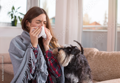 Girl covered with blanket blowing nose at home