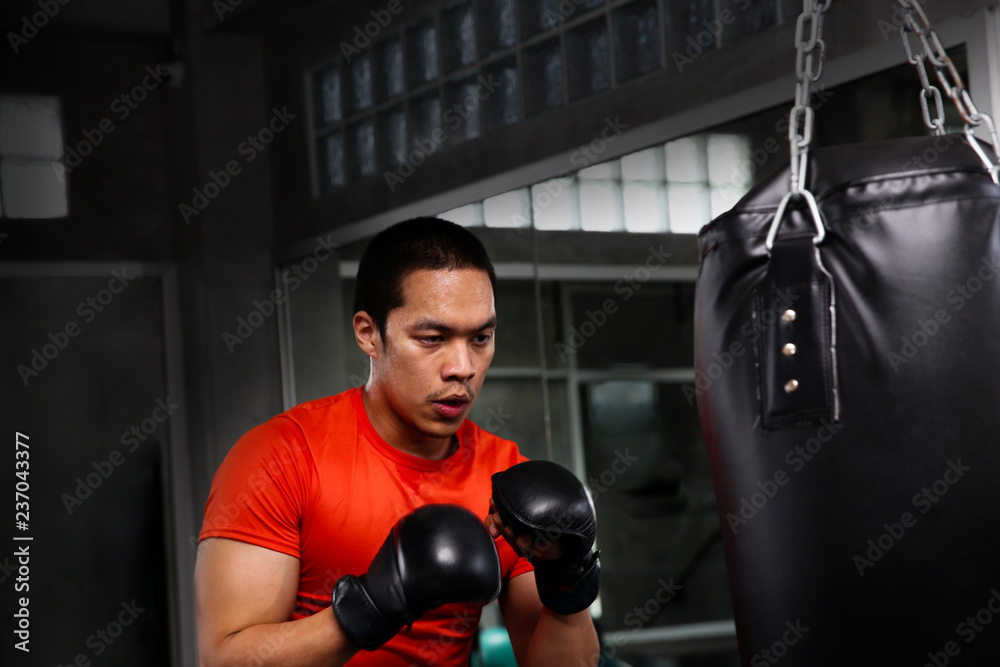 Athletes are punching in the gym. Male action of a boxing fighter training on a punching bag in the gym. Man boxer training is exercising with a punching bag at the sport club.