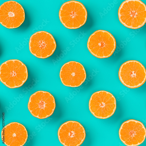 Fruit pattern of fresh mandarin slices on blue background. Flat lay, top view. Pop art design, creative summer concept. Half of citrus in minimal style. Tangerine.