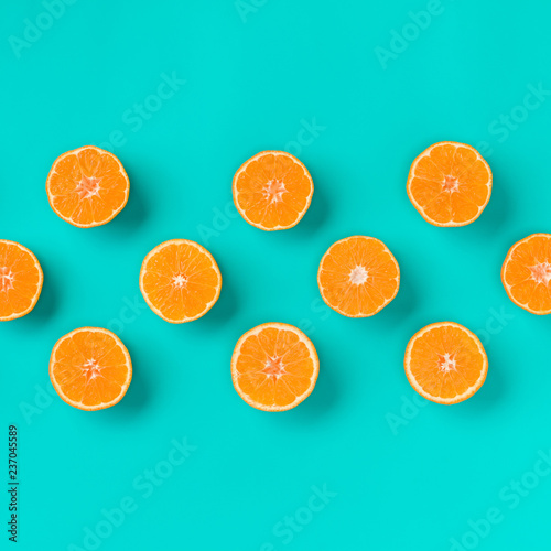 Fruit pattern of fresh mandarin slices on blue background. Flat lay, top view. Pop art design, creative summer concept. Half of citrus in minimal style. Tangerine.