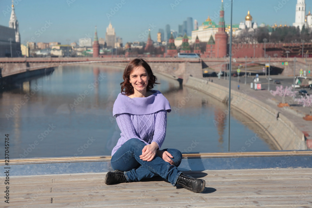 Young woman on a glass bridge on the background of the Moscow Kremlin.