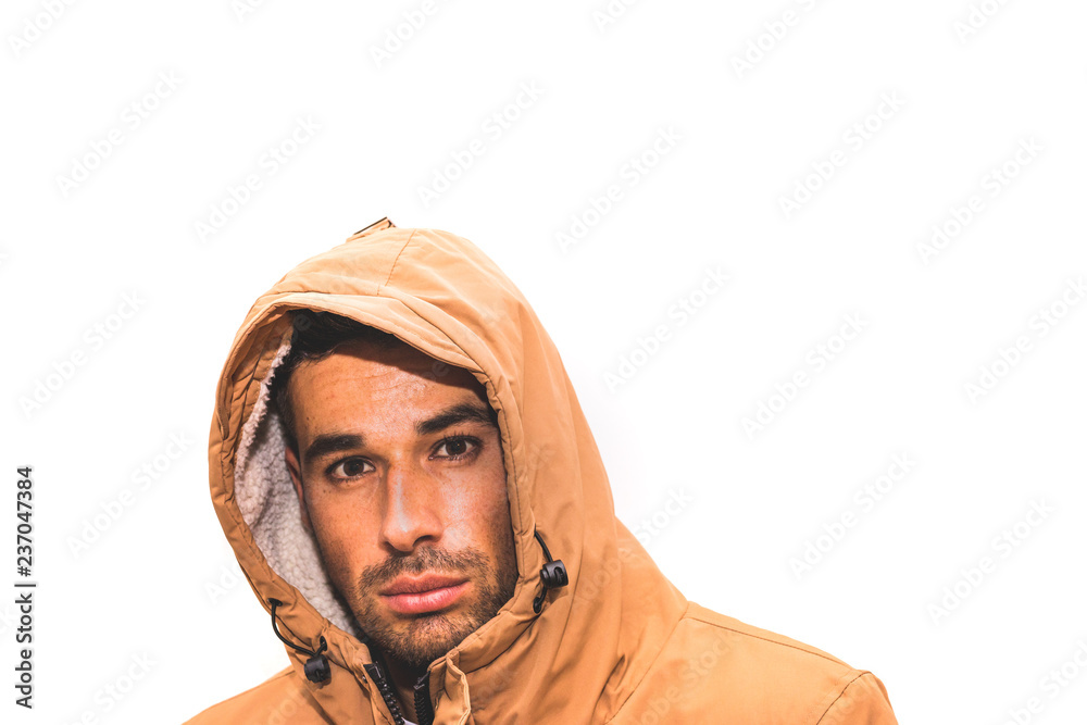 Junger Man im Winteroutfit mit Kapuze vor weißem Hintergrund
