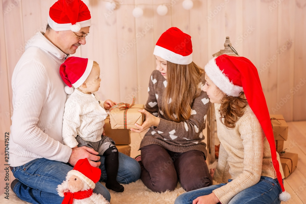 Fototapeta premium Christmas family photo of Christmas interior. Dad and three daughters with Christmas gifts