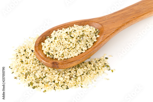 Heap of raw, organic hemp seeds on wooden spoon over white