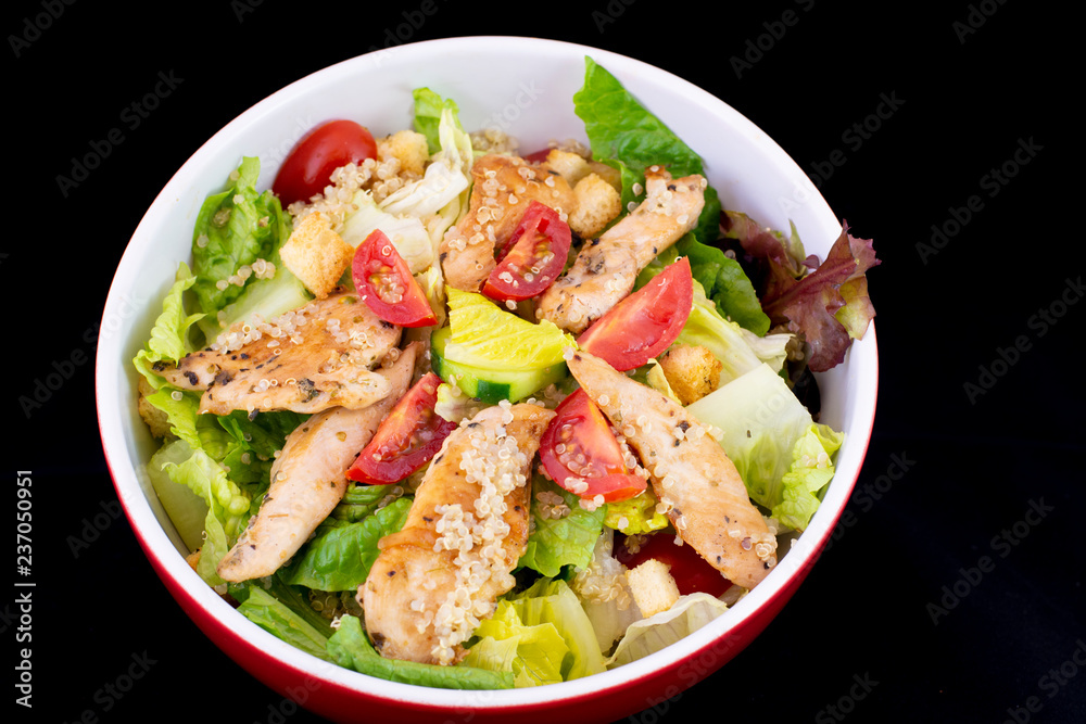 Chicken Quinoa salad with fresh vegetables with isolated black background Chicken Quinoa salad with fresh vegetables with isolated black background