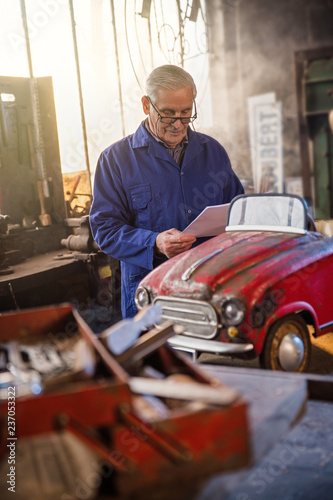 Senior man in his workshop repairing an old fashioned pedal car 