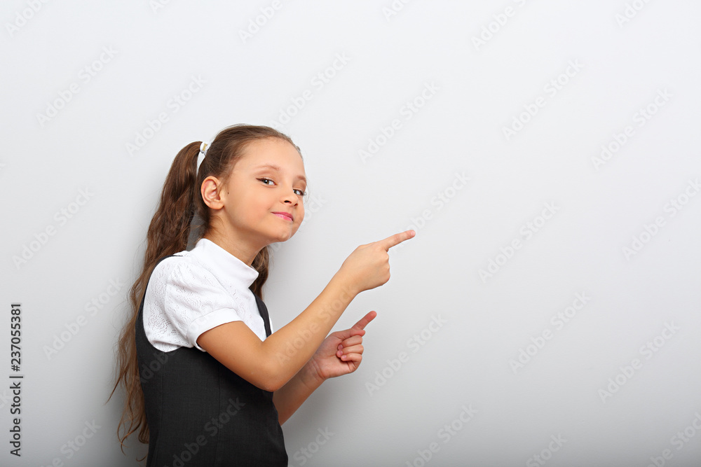 Beautiful excited fun kid girl pointing the two fingers on empty space blue background Beautiful excited fun kid girl pointing the two fingers on empty space blue background