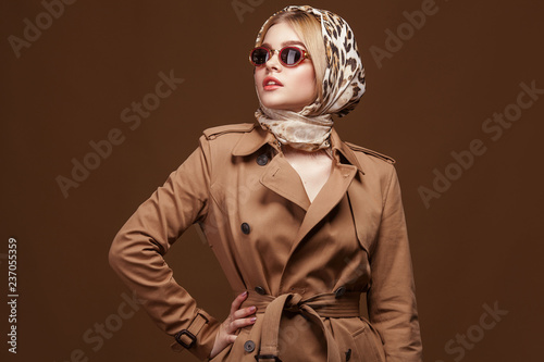 Foto Portrait of young beautiful woman in trendy trench coat over beige background