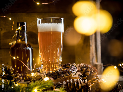 Beer in glass on wooden background with Christmas lights and pine cones