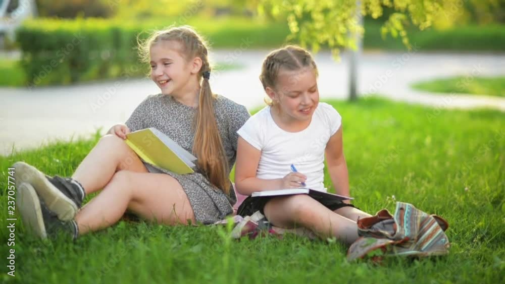 Two Funny Girls Are Playing with Books. They Are Smiling and Having a Lot of Fun. The Weather is Sunny. Two Funny Girls Are Playing with Books. They Are Smiling and Having a Lot of Fun. The Weather is Sunny.