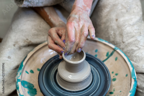 High angle above top view close up cropped photo of lady in her workwear with dirty hands she sit inside workspace made tableware or dishes stuff on circular wheel