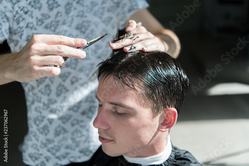 Hands of barber, scissors and comb. Guy getting haircut, close up