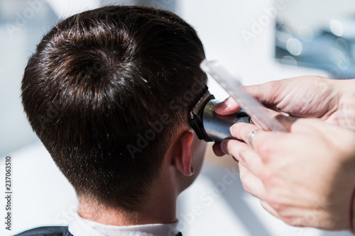 Haircut men barbershop. Barber using grooming professional haircutting machine to make haircut to client close up. Man haircut. Soft focus