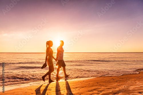 Obraz na plátně Couple walking on beach at sunset silhouettes - Romantic summer travel holidays