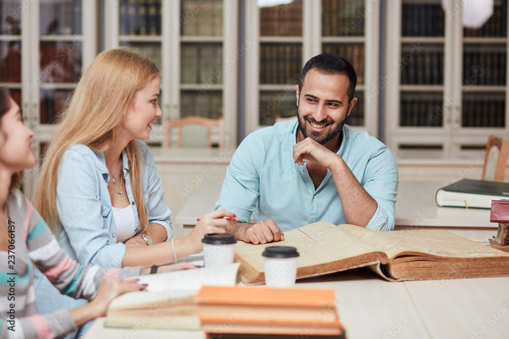 Happy young university students studying with books in library. Group of multiracial people in college library. Happy young university students studying with books in library. Group of multiracial people in college library.