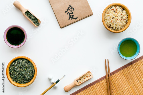 Chinese traditional symbols concept. Tea, rice, hieroglyph love, bamboo table mat, chopsticks, soy sause on white background top view frame copy space