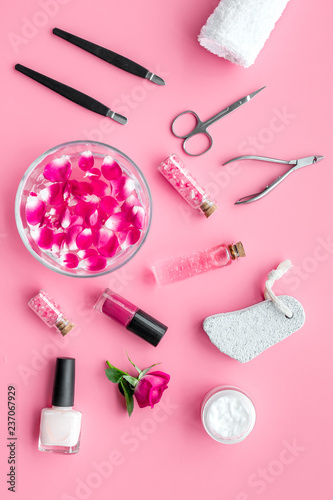 manicure equipment with nail polish and rose petals pink background top view
