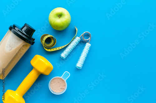 sport diet with protein nutrition and fitness equipment on blue background top view mock up