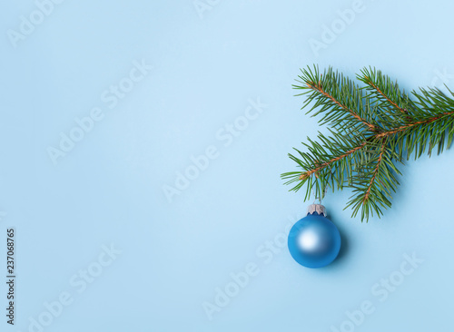 Evergreen coniferous tree with blue Christmas ball on blue background. New Year greeting card with place for text.