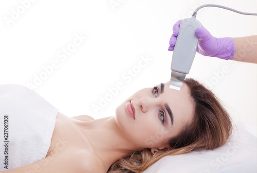 Hardware cosmetology. Closeup portrait of happy female face with closed eyes getting ultrasonic peeling in a beauty parlour.