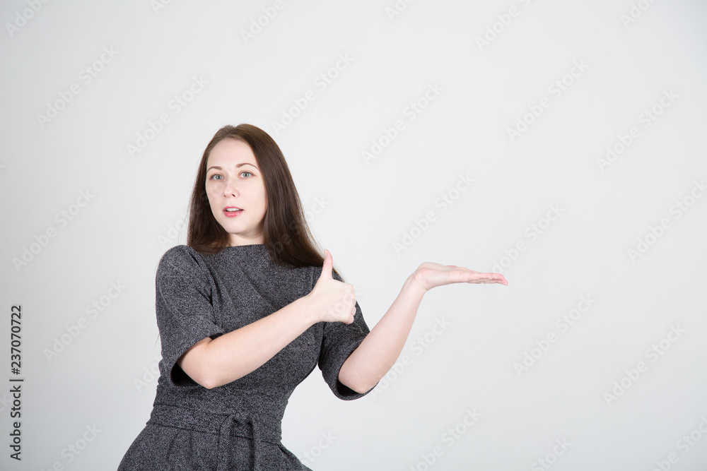 Young woman showing thumbs up over gray background Young woman showing thumbs up over gray background