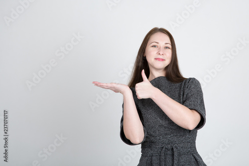 Young pretty woman showing thumbs up over gray background