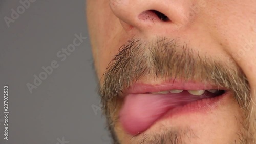 man with mustache licks his lips by tongue, two times, side view, closeup macro 
