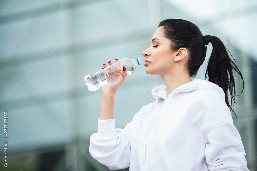 Fitness outdoor. Woman drinking bottle of water Fitness outdoor. Woman drinking bottle of water