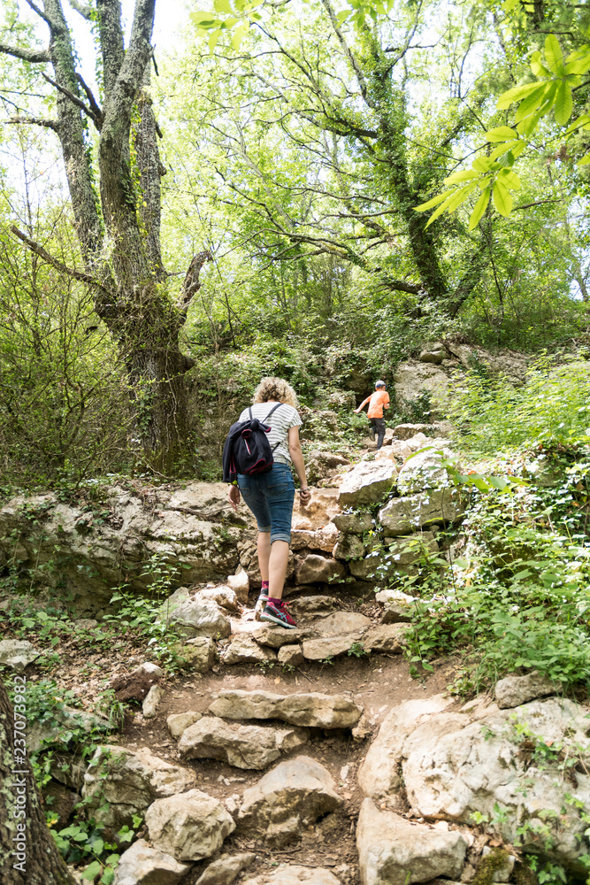 blonde woman hiking in the wild ardeche in france a small path