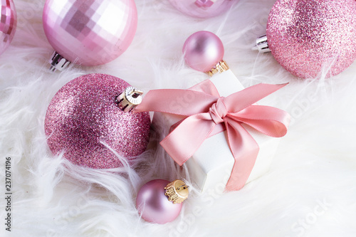 Pink Christmas decorations with gift box on white fur background close up
