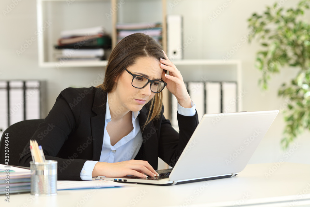 Worried office worker reading bad online news Worried office worker reading bad online news