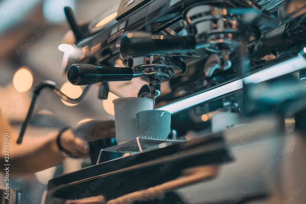 Hand of professional barista working in a coffee house preparing espresso coffee, on coffee machine. Concept of coffee making, service, catering