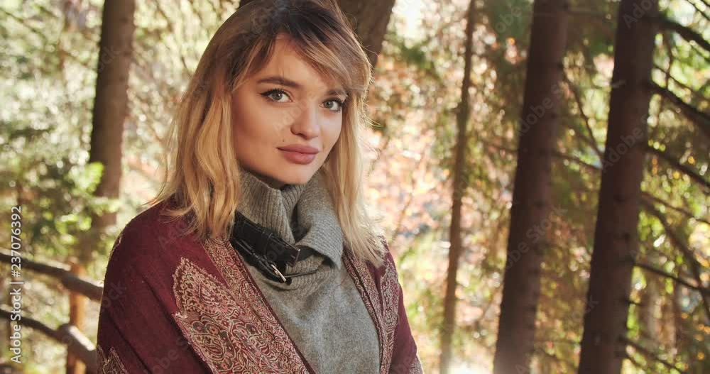 Close up view of Attractive Blond Woman Standing in the Autumn Park. Fascinating Look. Elegant Shawl. Big Beautiful Eyes. Pleasant Atmosphere. Tall Naked Trees in the Background. Close up view of Attractive Blond Woman Standing in the Autumn Park. Fascinating Look. Elegant Shawl. Big Beautiful Eyes. Pleasant Atmosphere. Tall Naked Trees in the Background.