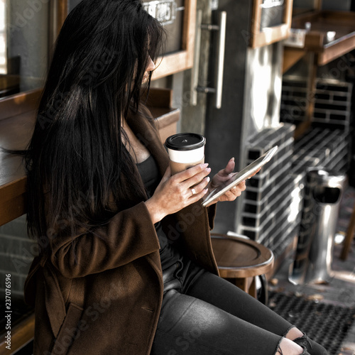 Beautiful girl drinks coffee, sitting in a cozy cafe.