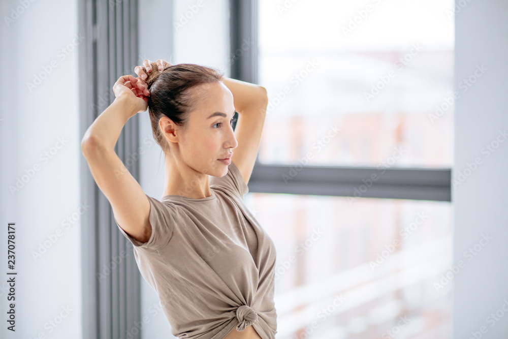 young awesome woman ddoing a hairbun before yoga classes. close up side view photo. young awesome woman ddoing a hairbun before yoga classes. close up side view photo.