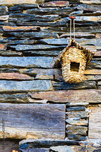 Wicker artificial nest on the facade of a slate house photo
