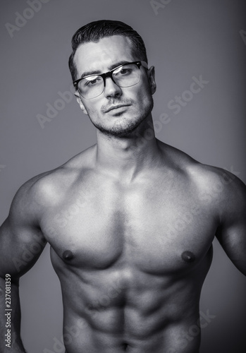 Black&white portrait of handsome shirtless young man in glasses. Perfect hair & skin. Close up. Studio shot