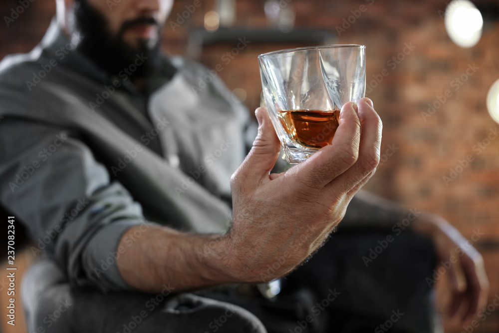 Man with glass of whiskey indoors, closeup Man with glass of whiskey indoors, closeup