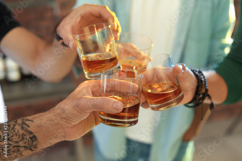 Billede på lærred Friends toasting with glasses of whiskey indoors, closeup