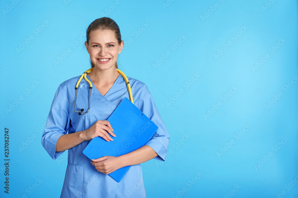 Portrait of young medical assistant with stethoscope and clipboard on color background. Space for text Portrait of young medical assistant with stethoscope and clipboard on color background. Space for text